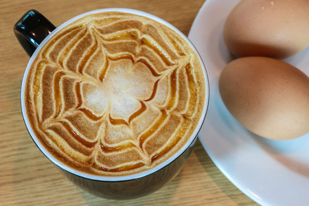 Hot coffee and soft focus of eggs on a wooden table background, Breakfast table