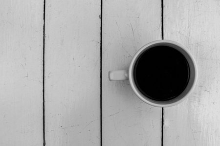Top view of black coffee cup on white wooden table backgroundの写真素材