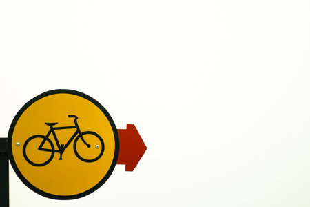 Round yellow color traffic signboard indicating bicycle lane with red arrow