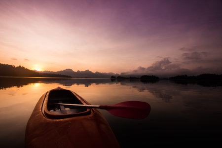 Red canoe boat on the lake with beautiful sunset scene