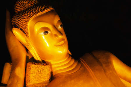 Reclining Buddha gold statue face in black backgroundの写真素材