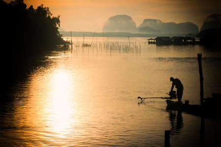 silhouette of fisherman working on sunrise sceneの写真素材