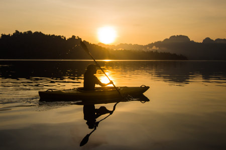 Silhouette man kayaking at sunriseの写真素材
