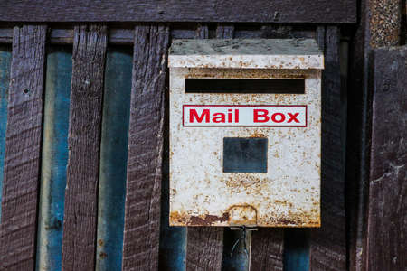 Mailbox hanging on wooden fence, Old white mailboxの写真素材
