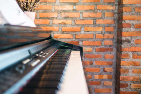 Side view piano keyboard. Blur piano foreground. Blur red brick wall background.の写真素材