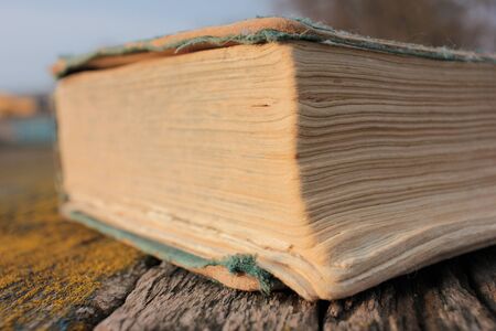 Old shabby book on a rough wooden table covered with moss outdoors.の写真素材