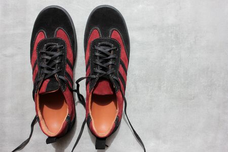 Pair of orthopedic sports shoes on a gray concrete background with copy space. Close-up of suede burgundy orthopedic sneakers from aboveの写真素材