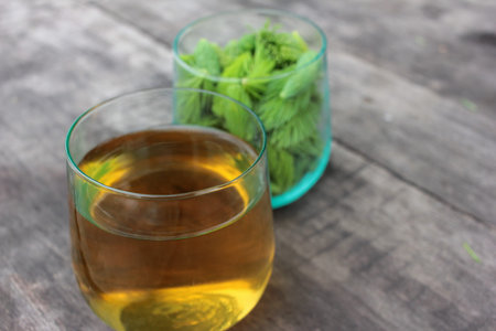 Spruce Tips tea in glass on wood table. Close up of conifer young green cones on rustic backgroundの写真素材
