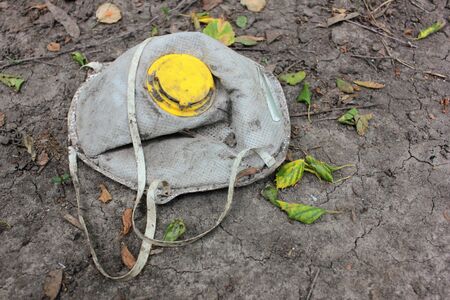 Disposable respirator with a yellow valve on the ground. Used face mask dumped on the ground during the Covid-19 pandemic.の写真素材