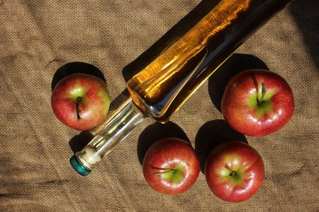 Homemade apple cider and fresh apples on a burlap background, top view, copy space.の写真素材