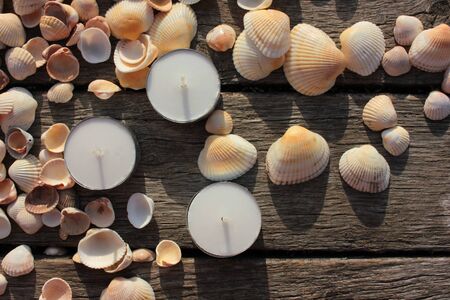 Tea candles and seashells on the beach wooden pier. Summer romantic eveningの写真素材
