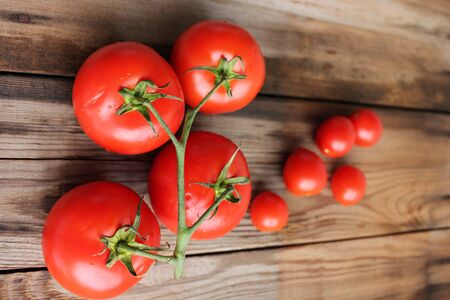 Fresh tomatoes on the vine and cherry tomatoes on rustic wooden tableの写真素材