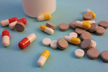 Medicine bottle, multicolored pills and capsules on blue background with copy space. Top view, selective focusの写真素材