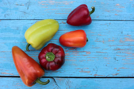 Red, yellow and orange bell peppers on light blue wooden background. Close-up. Fresh summer or autumn vegetables harvestの写真素材