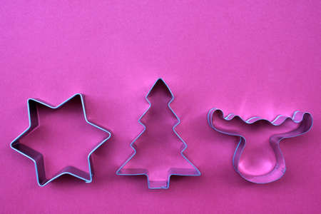 Steel Christmas tree, star, and deer shaped cookie cutters on red background with copy space.の写真素材