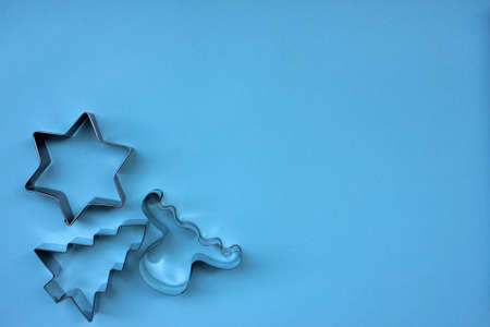 Steel Christmas tree, star, and deer shaped cookie cutters on blue background with copy space.の写真素材