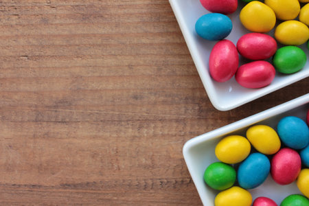 Colorful jelly beans candies in a bowl on wooden background. Sweet holiday treats for kids