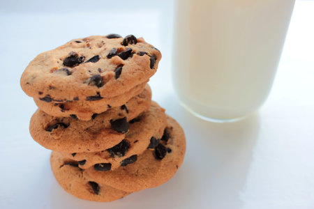 Glass of milk and chocolate chip cookies on white background. View from above. Close-up. Copy space
