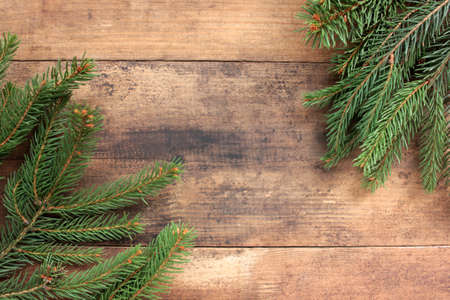 Christmas background with fir branches. Winter holidays frame with evegreen twigs on wooden board table. Flat lay, copy spaceの写真素材