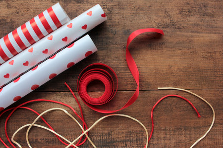 Red and white wrapping paper and ribbons on wooden table. Holiday background. Top view, copy space