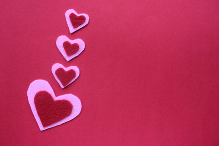 Handmade hearts made of felt fabric on red background. Flat lay valentine`s day composition. Copy...