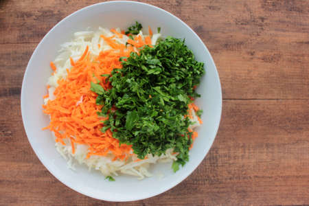 Salad with carrot and cabbage with parsley. Fresh vegetable ingredients in a bowl.の写真素材