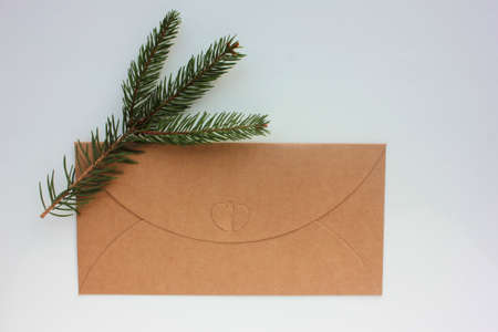 Craft envelope with heart on white background. Christmas card with christmas tree twig. Top view, copy space.の写真素材