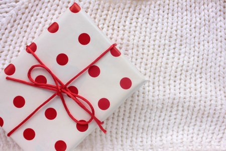 Gift box wrapped in red and white wrapping paper and tied with ribbon and on white background. Overhead view of table with present.の写真素材