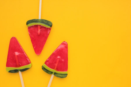 Watermelon ice creams on yellow colored backdrop. Bright summer background. Lollipop in piece of...