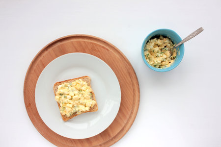 Egg salad sandwich with whole wheat toasted bread and microgreens on plate on white background....
