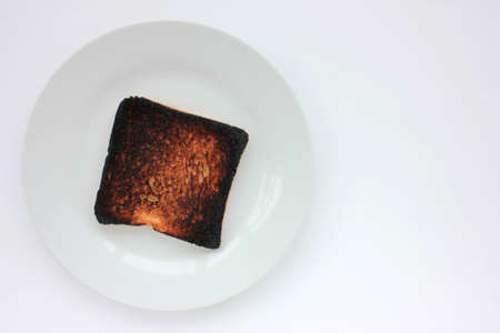 Piece of burnt toast bread on a plate on a white background. Top view, copy spaceの写真素材