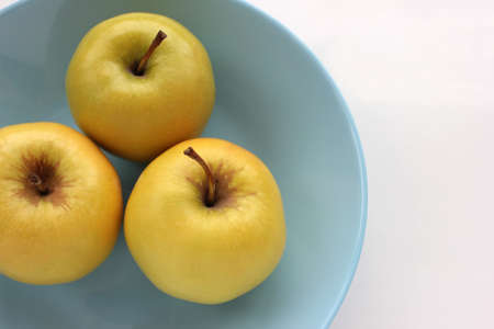 Green apple on blue plate. Overhead view of fresh fruits on white table background. Copy spaceの写真素材