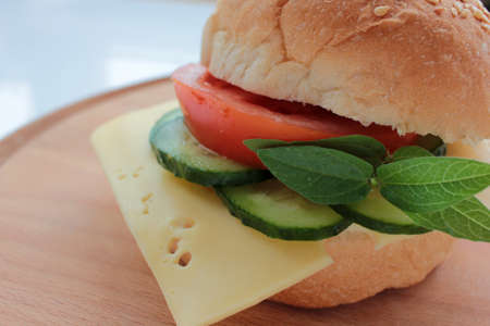 Cheese burger with tomato, cucumber and greens on white background. Healthy fast food. Sandwich with fresh vegetables.の写真素材