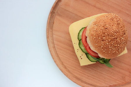 Cheese burger with tomato, cucumber and greens on white background. Healthy fast food. Sandwich with fresh vegetables.の写真素材