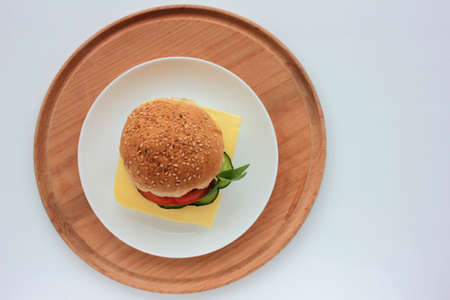 Cheese burger with tomato, cucumber and greens on white background. Healthy fast food. Sandwich with fresh vegetables.の写真素材