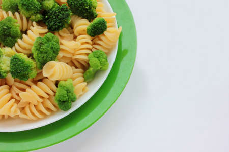 Fusilli pasta with broccoli in garnish dish on white background. Overhead view of vegetable pasta salad with steam. Copy spaceの写真素材