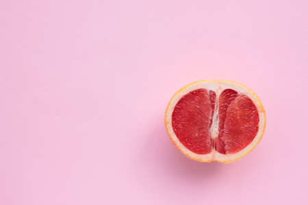 Grapefruit cut in half on a pink background. Close-up of citrus fruit on a colored backdrop. Top view. Copy spaceの写真素材