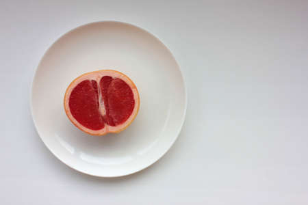 Half of grapefruit on a plate on a white background. Top view, copy space.の写真素材