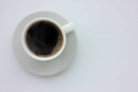 Cup of black hot espresso coffee with steam on white background. Top view, copy space. Morning espresso on table.の写真素材