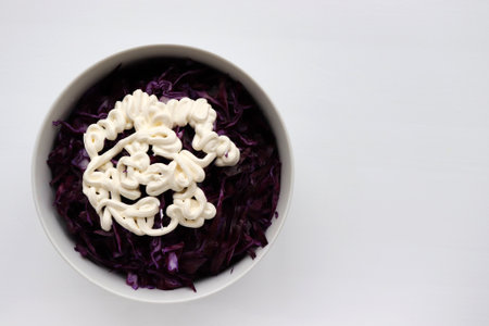 Easy homecooked creamy coleslaw from red cabbage in a bowl on white table background. Top view, copy space. Fresh vegetable salad with mayonnaise dressing. Flat lay food. Healthy eating conceptの写真素材