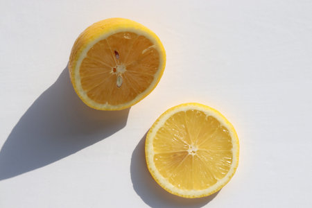 Half of lemon and citrus slice on white table background. Top view, copy space. Hard light, shadow....