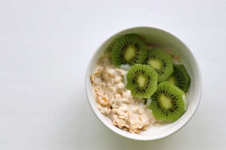 Healthy breakfast yogurt with oatmeal and kiwi in bowl on a white table background. Top view. Copy spaceの写真素材