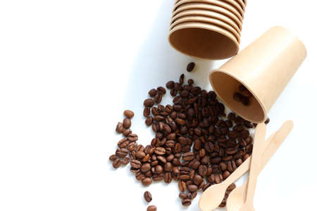 Flat lay composition with coffee beans, kraft paper cup and wooden spoon. Top view, copy spaceの写真素材