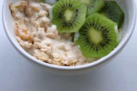 Healthy breakfast yogurt with oatmeal and kiwi in bowl on a white table background. Top view. Copy spaceの写真素材
