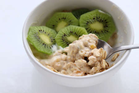 Healthy breakfast yogurt with oatmeal and kiwi in bowl on a white table background. Top view. Copy spaceの写真素材