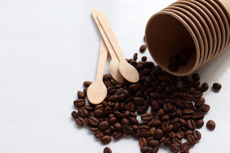 Flat lay composition with coffee beans, kraft paper cup and wooden spoon. Top view, copy spaceの写真素材