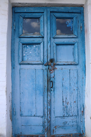 Old wooden door with lock painted in blue. Cracked weathered wooden texture.の写真素材