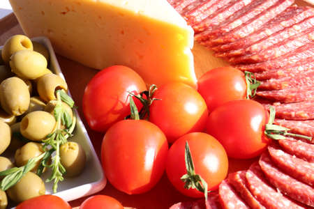 Salami cheese board with tomatoes and green olives on white table background. Set of appetizers. Flat lay food. Top view, copy spaceの写真素材