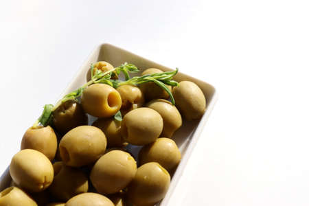 Close-up of green pickled olives on a plate on white table background. Top view, copy spaceの写真素材
