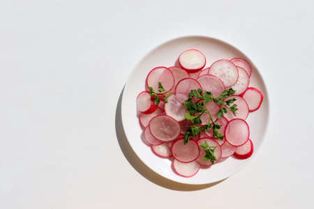 Fresh radish salad with parsley on white background. Top view, copy space. Spring summer vegetable salad on white plateの写真素材